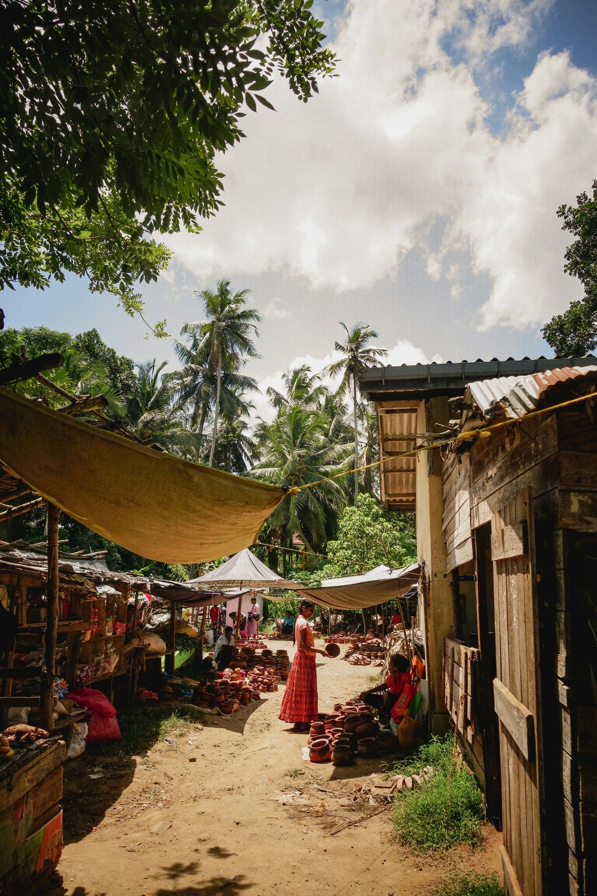 Village scene with people and market stalls under a cloudy sky.